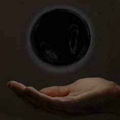 a person holding out their hand in front of a black object