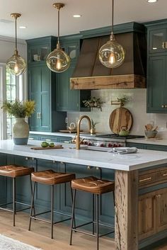 a kitchen with blue cabinets and stools in the center, an island counter has three hanging lights above it