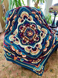 a crocheted blanket sitting on top of a wooden table next to a lamp