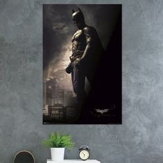 a batman poster hanging on the wall above a dresser