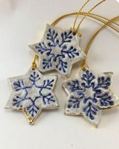 three blue and white snowflake ornaments on a gold chain