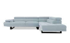 a light blue sectional sofa sitting on top of a white floor next to a footstool