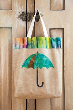 a bag with an umbrella painted on it hanging from a wooden door handle and the handles are made out of burlap