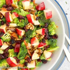 a white bowl filled with broccoli, apples and raisins