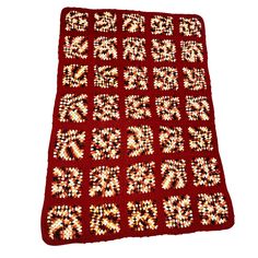 a red crocheted blanket with white and yellow flowers