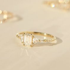 an engagement ring with three stones on top and two diamonds in the middle, sitting on a white surface