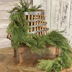 a wooden bench covered in greenery sitting on top of a hard wood floor