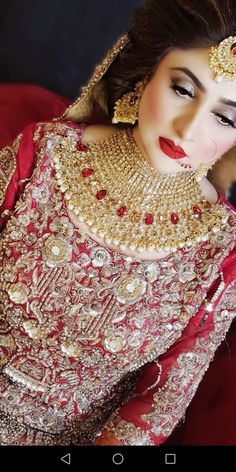 a woman wearing a red and gold bridal outfit