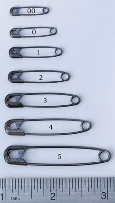 six pairs of scissors sitting next to a ruler