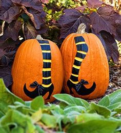 two pumpkins with faces painted on them sitting in the ground next to some plants