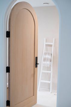 an open door leading to a white room with a ladder on the wall behind it