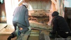 two men are working on an old fireplace