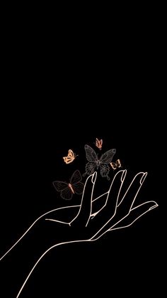 a person's hand holding a bunch of butterflies on a black background in the dark