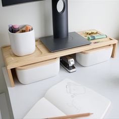 a desk with a laptop, pencils and other items on it next to a drawing pad