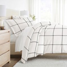 a bed with white sheets and black checkered comforter set on top of it