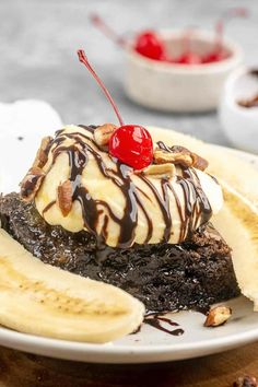 a banana split with ice cream, chocolate sauce and bananas on top is sitting on a white plate