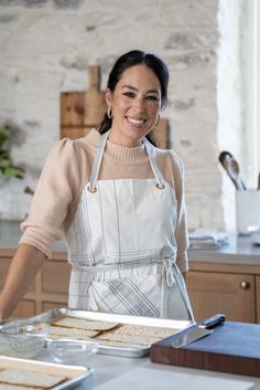 a woman standing in front of a table with food on it and smiling at the camera