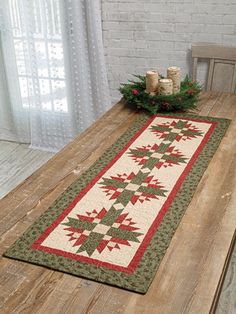 a wooden table topped with a green and red quilted placemat on top of a wooden table