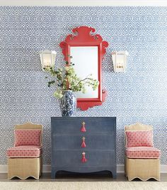 a blue and white room with a red mirror on the wall, two chairs and a dresser