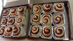 two boxes filled with cinnamon rolls sitting on top of a counter next to each other