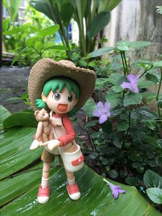 a figurine holding a teddy bear on top of a green leafy plant