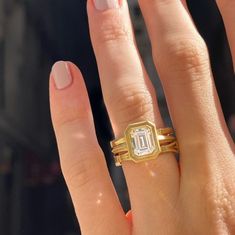 a woman's hand with two gold rings on it and a diamond ring in the middle