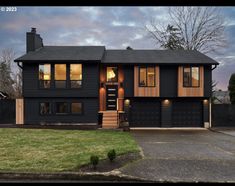 a large black house with lots of windows on it's sides and two car garages