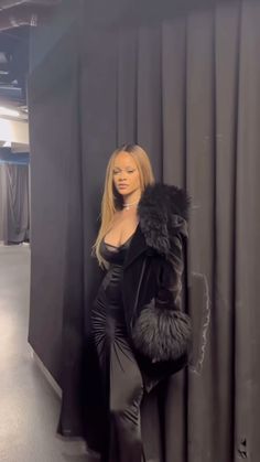 a woman standing next to a black curtain in front of a wall with fur on it