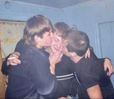 three young boys are hugging each other in a room with blue walls and wood trimmings