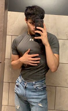 a man taking a selfie in front of a mirror with his hands on his hips