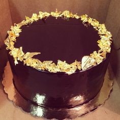 a large chocolate cake with gold decorations on it's side in a cardboard box