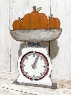 an old fashioned clock with pumpkins on top