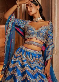 Features the gorgeous peacock blue taffeta lehenga blouse embellished with silver gota, resham and bead work with wine hues. Teamed with a matching blouse and an embellished belt. Completed with tulle dupatta consisting of beautiful gota, resham and beadwork embellishments with a vibrant wine contrast. Composition : Lehenga and Blouse- Taffeta, Dupatta- Tulle Care: Dry Clean Only and Vacuum Storage This product can be customised for sleeves, length of blouse and neckline Delivery : 6-8 weeks as the product is hand crafted. Check Size Guide or choose MySize for free customisation (All Sizes above XL can be made at 15% additional cost) For more information and sizes please contact fabiliciousfashion@gmail.com or visit our Copenhagen studio.About the Designer : Nikita Gujral’s collection of b Lehenga Belt, Designing Clothes, Blouse Yoke, Belt Blouse, Making Clothes, Embellished Belt, Beadwork Embroidery, Indian Dresses Traditional, Lehenga Blouse