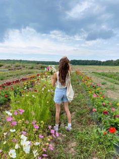 a woman standing in the middle of a field with flowers