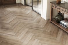 a room with wood flooring and a vase on the table in front of it