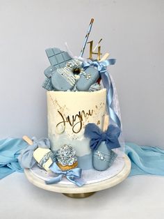 a blue and white birthday cake with baby shoes on the top, sitting on a table