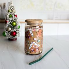 a glass jar with gingerbread cookies on it next to a christmas tree and green pencil