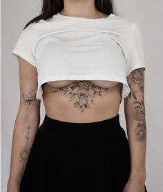 a woman with tattoos on her stomach wearing a white crop top