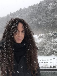 a woman with long curly hair standing in the snow