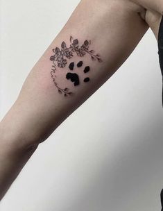 a woman's arm with a dog paw and flower tattoo on the left forearm