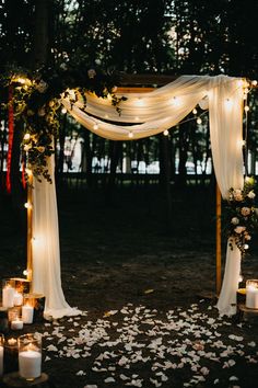 an outdoor wedding ceremony with candles and flowers on the ground, surrounded by greenery