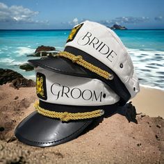 two hats sitting on top of a beach next to the ocean