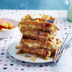 a stack of waffles on a plate with syrup drizzled over them