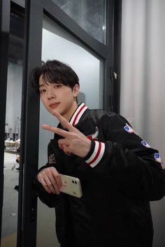 a young man pointing at the camera while standing in front of a door with his finger up