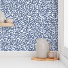 a blue and white floral wallpaper with two vases on the shelf next to it