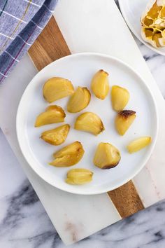 peeled pineapples on a white plate next to a wooden cutting board