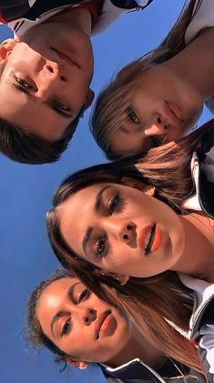 four girls are standing in a circle and looking up at the camera with their eyes closed