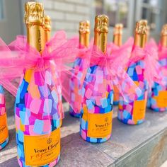 several bottles of champagne are lined up on a table with pink ribbons and bows around them