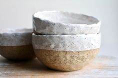 three white and brown bowls sitting on top of a wooden table