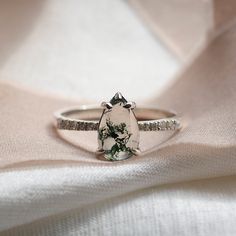 a diamond ring sitting on top of a white cloth